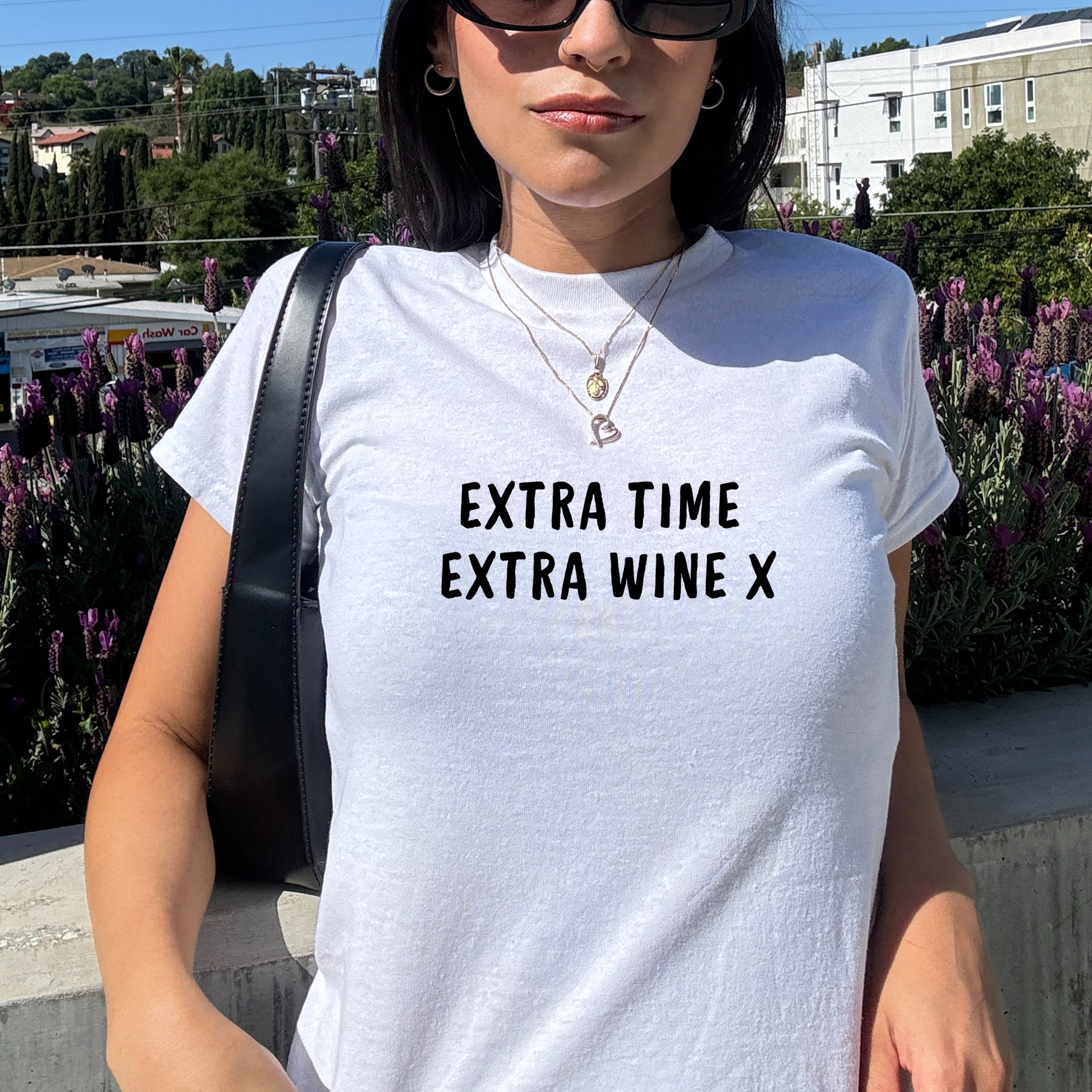 White fitted baby tee with black “Extra Time Extra Wine X” slogan, styled casually with a shoulder bag, perfect for football match days and wine lovers