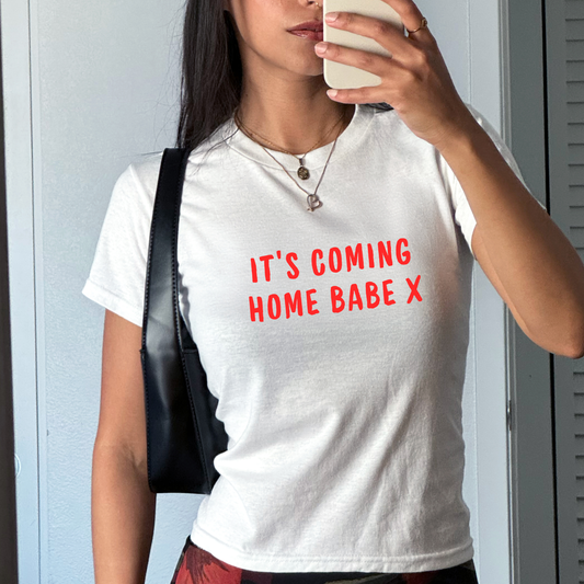 White fitted baby tee with bold red “It’s Coming Home Babe X” slogan, styled casually with a shoulder bag, perfect for England football match days and summer outfits