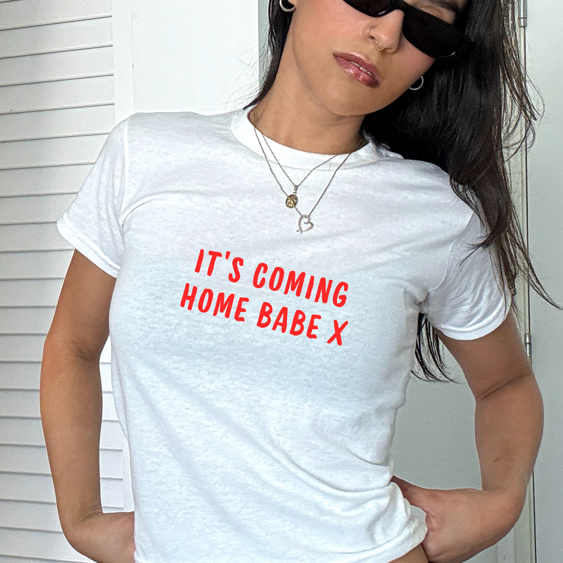 White fitted baby tee with bold red “It’s Coming Home Babe X” slogan, styled casually with a shoulder bag, perfect for England football match days and summer outfits