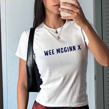 White fitted baby tee with navy “Wee McGinn X” slogan, styled casually with a shoulder bag, perfect for Scotland football fans and match day outfits